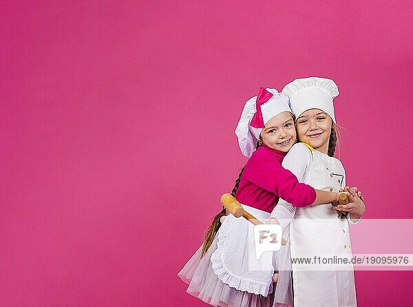 Zwei Mädchen kocht Küchenutensilien umarmen