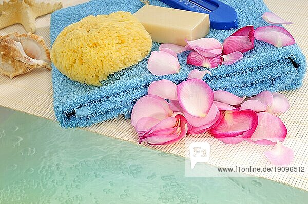Handtuch  Rosenblütenblätter  Seife  Schwamm und Muschel auf einer Ablage über einer gefüllten Badewanne