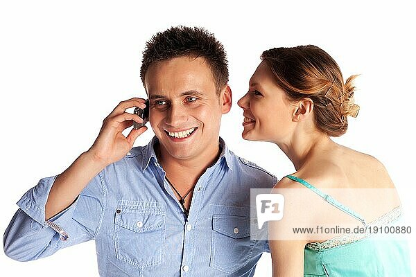 Fröhliches junges Paar beim Telefonieren vor weißem Hintergrund