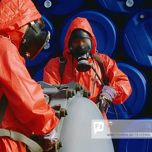 2 M?aenner bei der Bef?llung eines Chemikalienbehaelters in roten Schutzanzügen mit Atemschutzmasken. Digital und 6x6 Dia