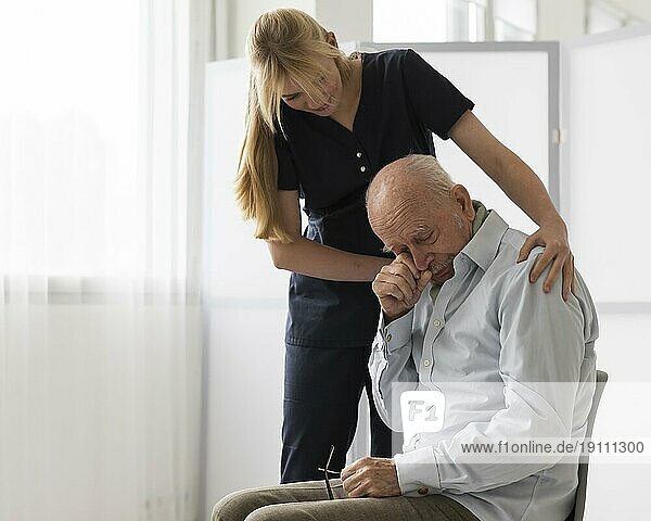 Krankenschwester tröstet weinenden alten Mann