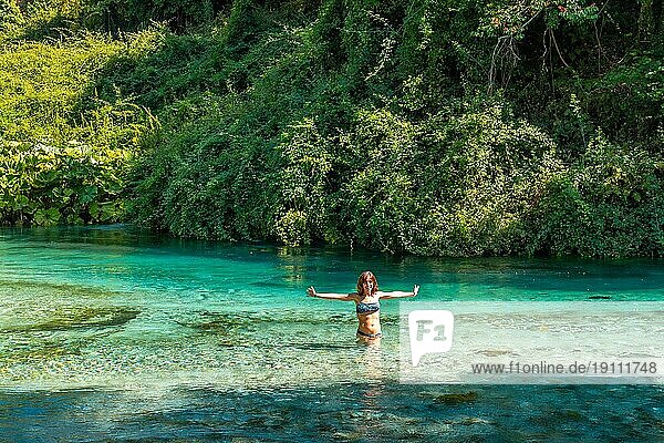 Ein Tourist badet lächelnd im kalten Wasser des Flusses Das Blaue Auge oder Syri i kalter in den Bergen Südalbaniens