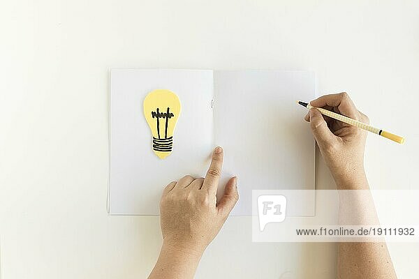 Menschliche Hand schreibt Karte mit Glühbirne
