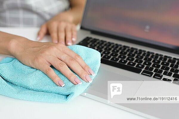 Frau reinigt Laptop zu Hause von Hand