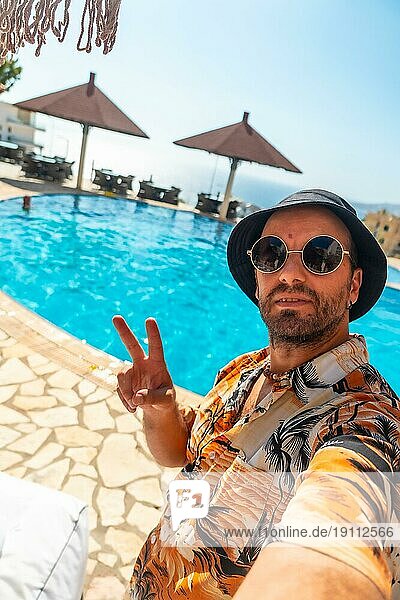 Tourist Mann im Hotelpool im Sommer ein Selfie genießen den Urlaub  so dass der Sieg Symbol