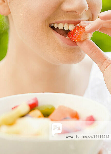 Close up of a young woman biting a strawberry