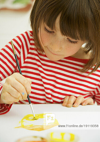 Portrait of young girl painting with watercolor