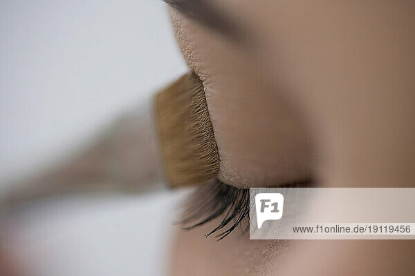 Close up of young woman eye with eyeshadow brush