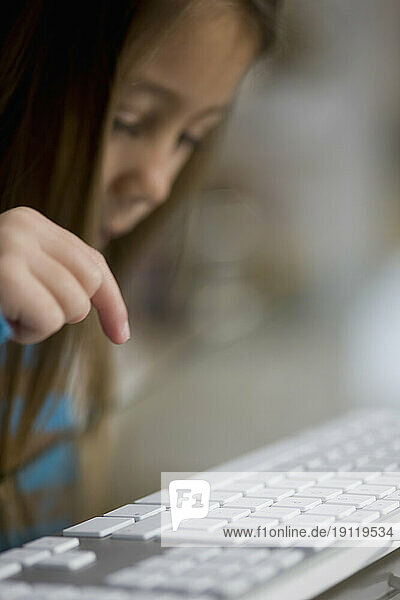 Close up of little girl hand typing on computer keyboard
