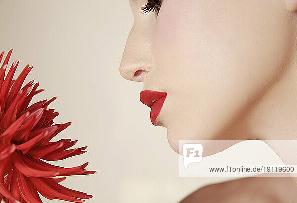 Close up of young beautiful woman inhaling red dahlia