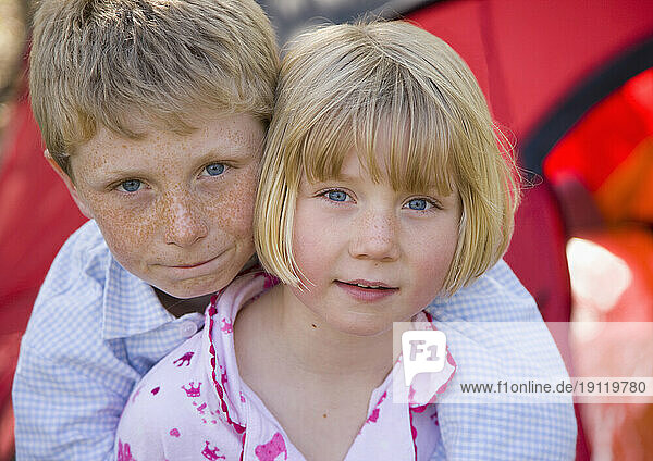 Close up of boy and girl embracing outside tent