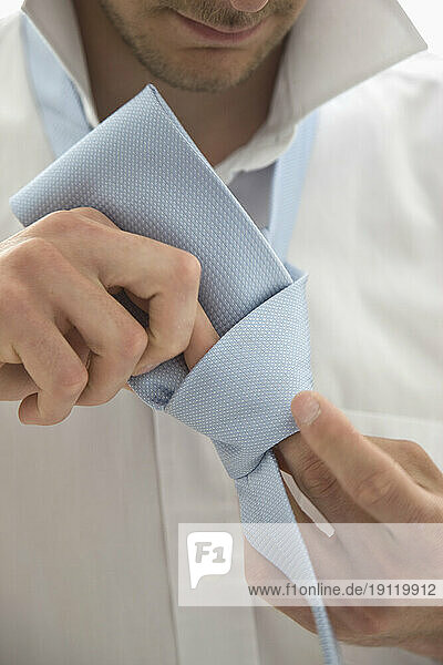 Close up of a young man tying a tie knot