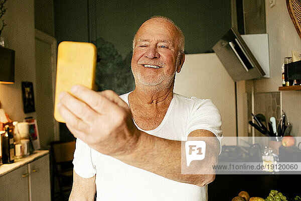 Glücklicher älterer Mann nimmt Selfie durch Smartphone in der Küche