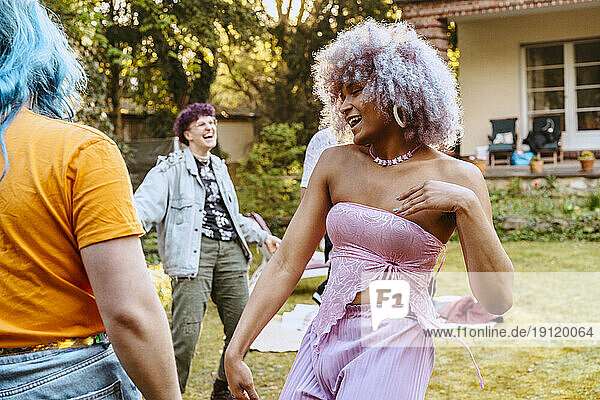 Carefree transwoman dancing with LGBTQ friends during dinner party in back yard