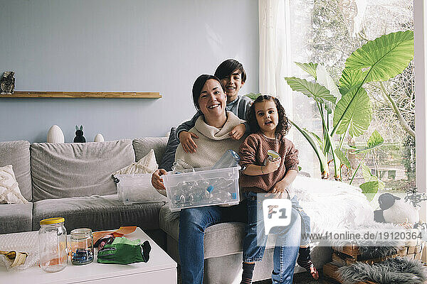 Porträt einer fröhlichen Familie mit Plastikmüll  die zu Hause im Wohnzimmer sitzt