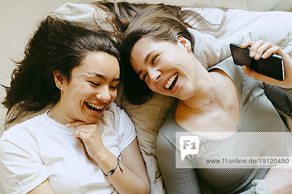 Happiness female friends lying on bed at home