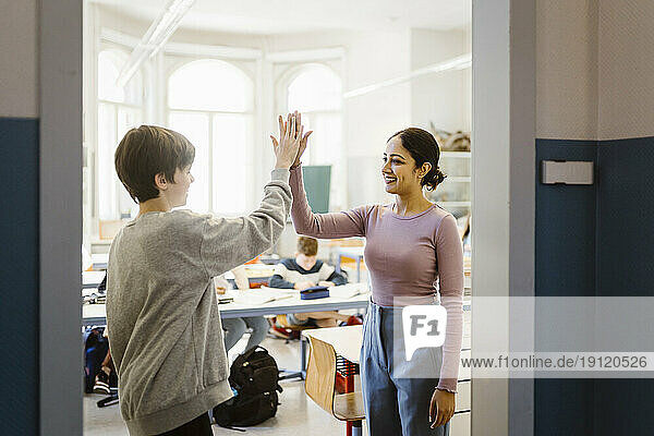 Eine lächelnde Lehrerin gibt einem Schüler im Klassenzimmer ein High-Five