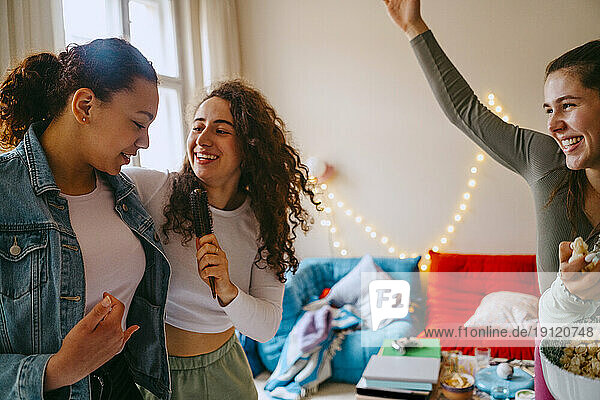 Glückliche Freundinnen  die sich beim gemeinsamen Singen zu Hause vergnügen