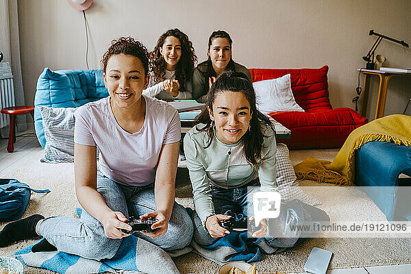 Glückliche Freundinnen spielen ein Videospiel im Wohnzimmer zu Hause
