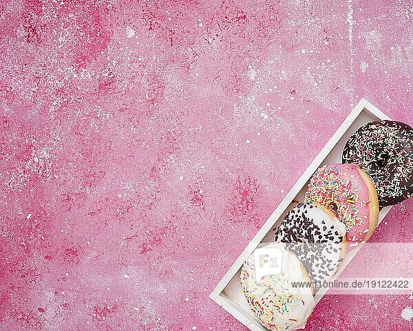 Erhöhte Ansicht Donuts weißen Holzkiste Ecke rosa Hintergrund