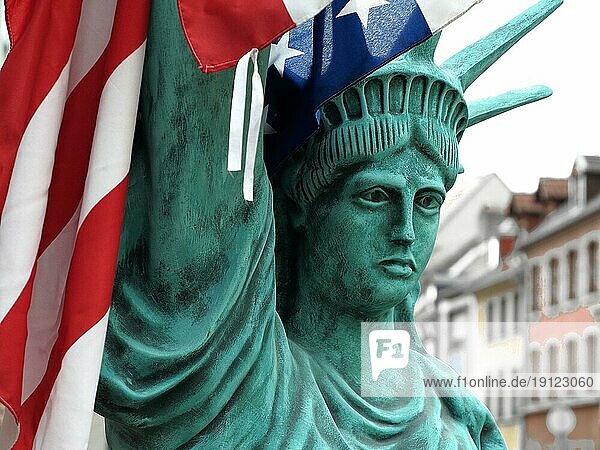 Figur der Freiheitsstatue mit US-Flagge  Hintergrund Häuser  aufgenommen mit Tiefenschärfe