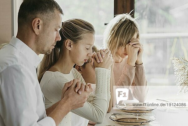 Schöne Familie  die vor dem Essen gemeinsam betet
