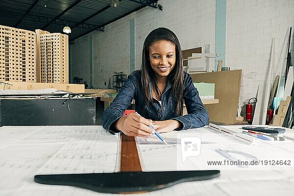 Glückliche afroamerikanische Dame mit großem Lineal Stift Tisch