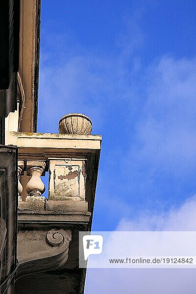 Seitenansicht eines Balkons mt reichen Verzierungen  an dem die Zeit nicht spurlos vorübergegangen ist  Hintergrund blaür Himmel