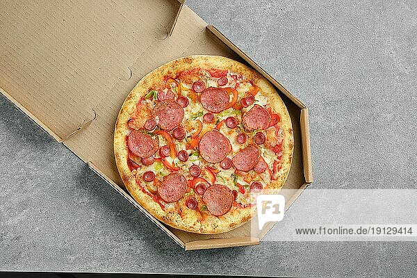 Draufsicht auf Pizza mit Wurst und bunter Paprika im Karton