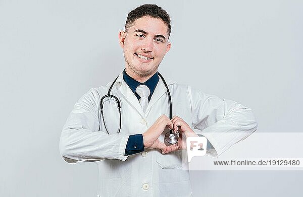 Junger lateinischer Arzt macht Herzform auf isoliertem Hintergrund. Freundliche Arzt macht Herz Geste mit Händen isoliert