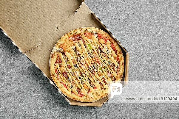 Draufsicht auf Pizza mit dünner Wurst  Jalapeno und Champignon im Karton