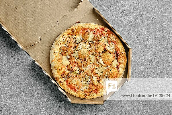 Draufsicht auf eine Pizza mit Hähnchen  Käse und Ananas in einer Pappschachtel