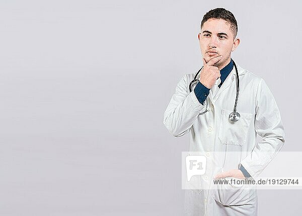 Nachdenklicher Arzt Mann schaut auf. Junger Arzt nachdenklich und aufblickend isoliert  Arzt nachdenklich mit Hand am Kinn