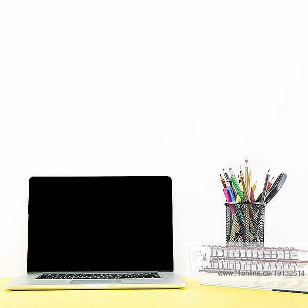 Stacked Notebook mit verschiedenen Stiften Bleistifthalter in der Nähe Laptop Schreibtisch