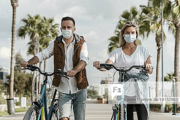 Menschen fahren Fahrrad und tragen medizinische Maske