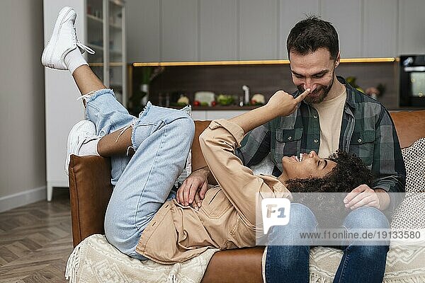 Glückliches junges Paar spielt auf dem Sofa
