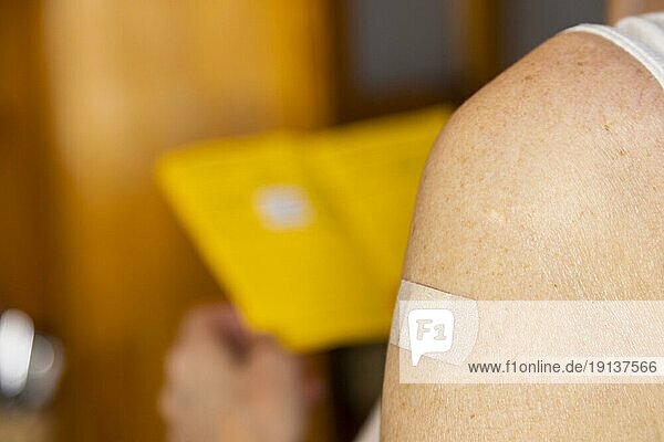Mit einem Coronawirkstoff geimpfte Frau schaut in ihren Impfausweis