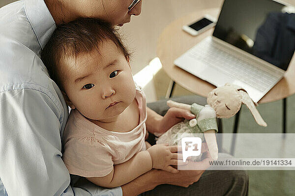 Cute daughter with father holding stuffed toy at home