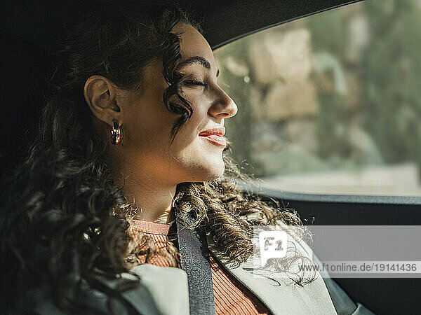 Woman enjoying sunlight sitting in car