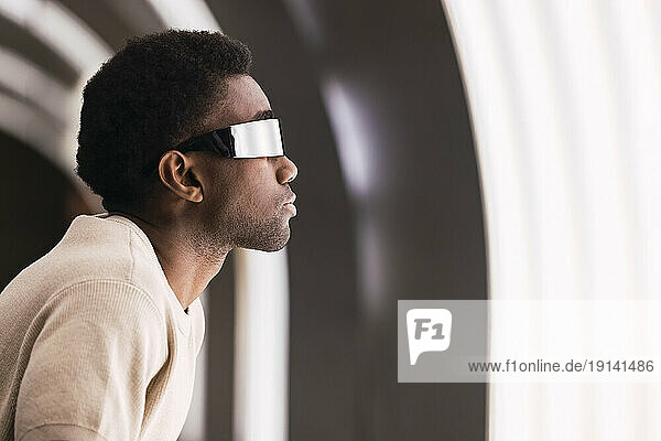 Futuristic man with cyber glasses looking at light pane