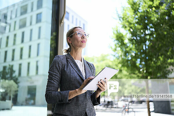 Businesswoman looking up holding tablet PC