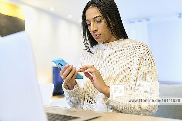 Woman wearing sweater using smart phone at home