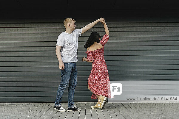 Young couple dancing in front of closed shutter