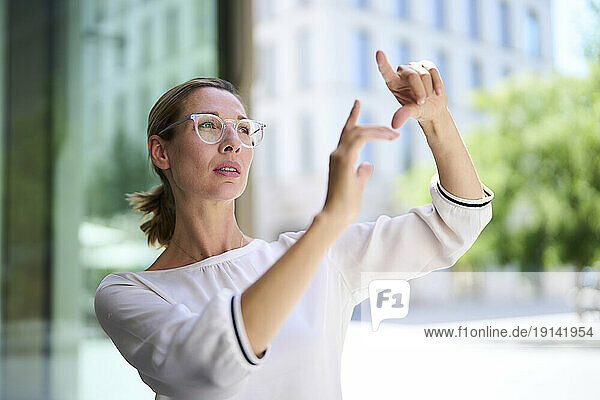 Focused businesswoman gesturing near building