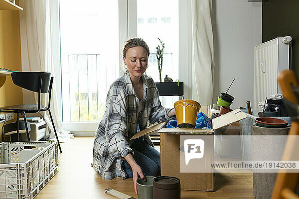 Young woman unpacking containers from cardboard box