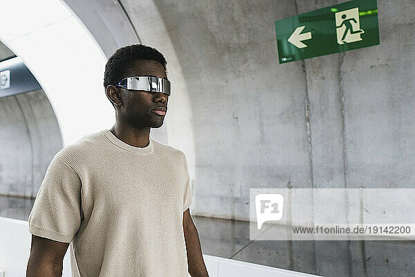 Young man wwdearing cayber glasses walking in metro tunnel