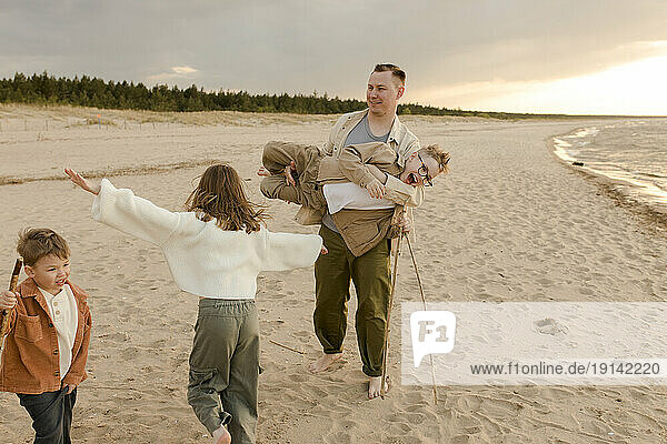 Father having fun with daughter and sons at beach