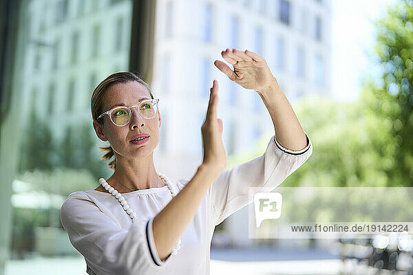 Businesswoman wearing eyeglasses and gesturing near building
