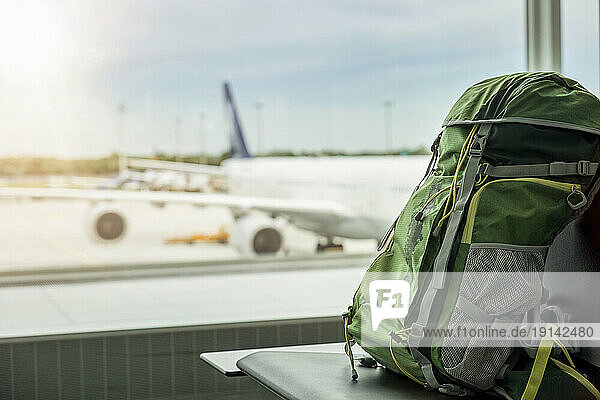 Backpack on seat with plane in background at airport