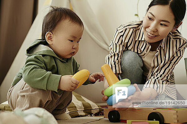 Mother giving toy to daughter crouching at home